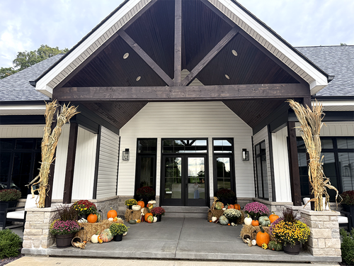 Autumn pumpkins, mums and cornstalks decorating a grand covered front entrance